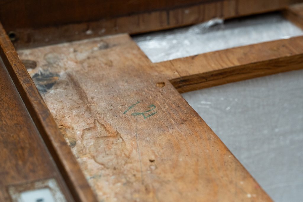 Four fabrication IDs “12” are twice stamped, one each written in carbon pencil or green pencil on the lectern’s interior components. These are often found in cabinetmaking shops to identify sections dedicated to a single piece of furniture when multiple units of the same shape but for idiosyncratic decorative matched surfaces such as the walnut veneer this group of lecterns. / Photograph by Aaron Rodriguez